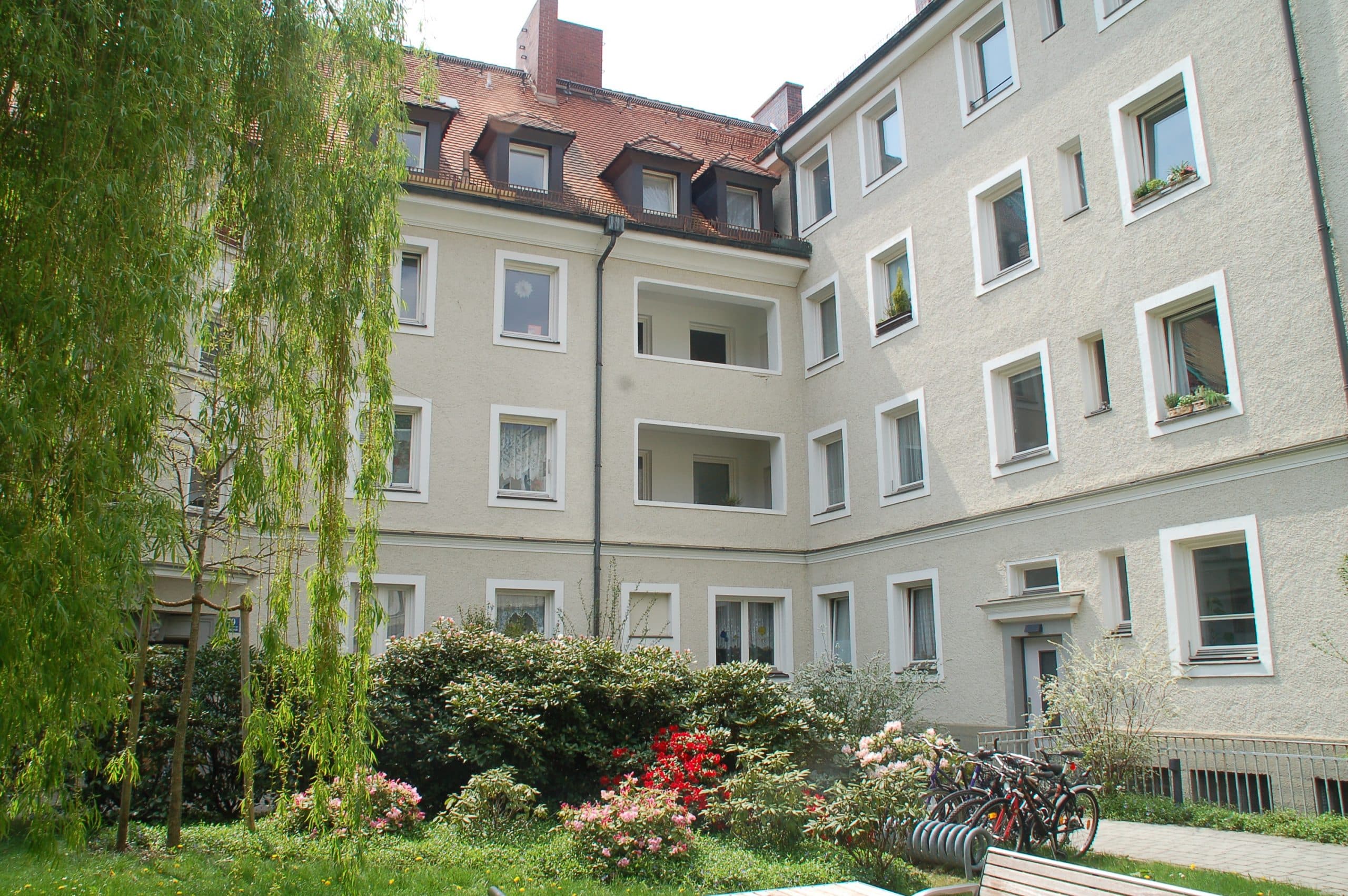 Innenhof der Genossenschaft Bauverein Giesing mit Trauerweide, Rhododendren und Fahrrädern