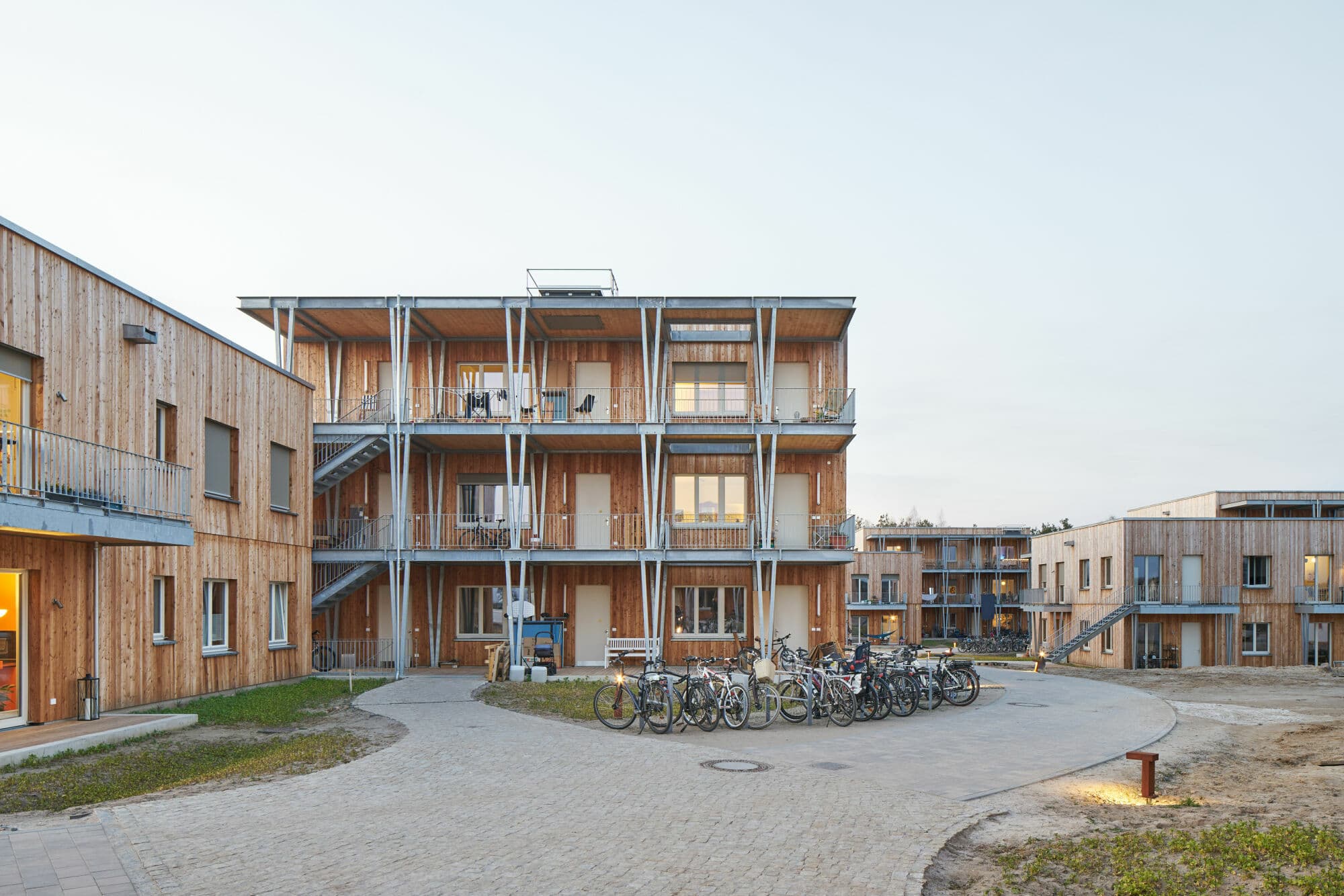 Genossenschaftliche Holzbauten um einen gepflasterten Hof mit Fahrrädern