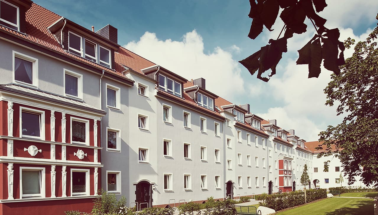 Sanierte Wohnhäuser der Genossenschaft Espabau mit weißer und roter Fassade und grünem Hof