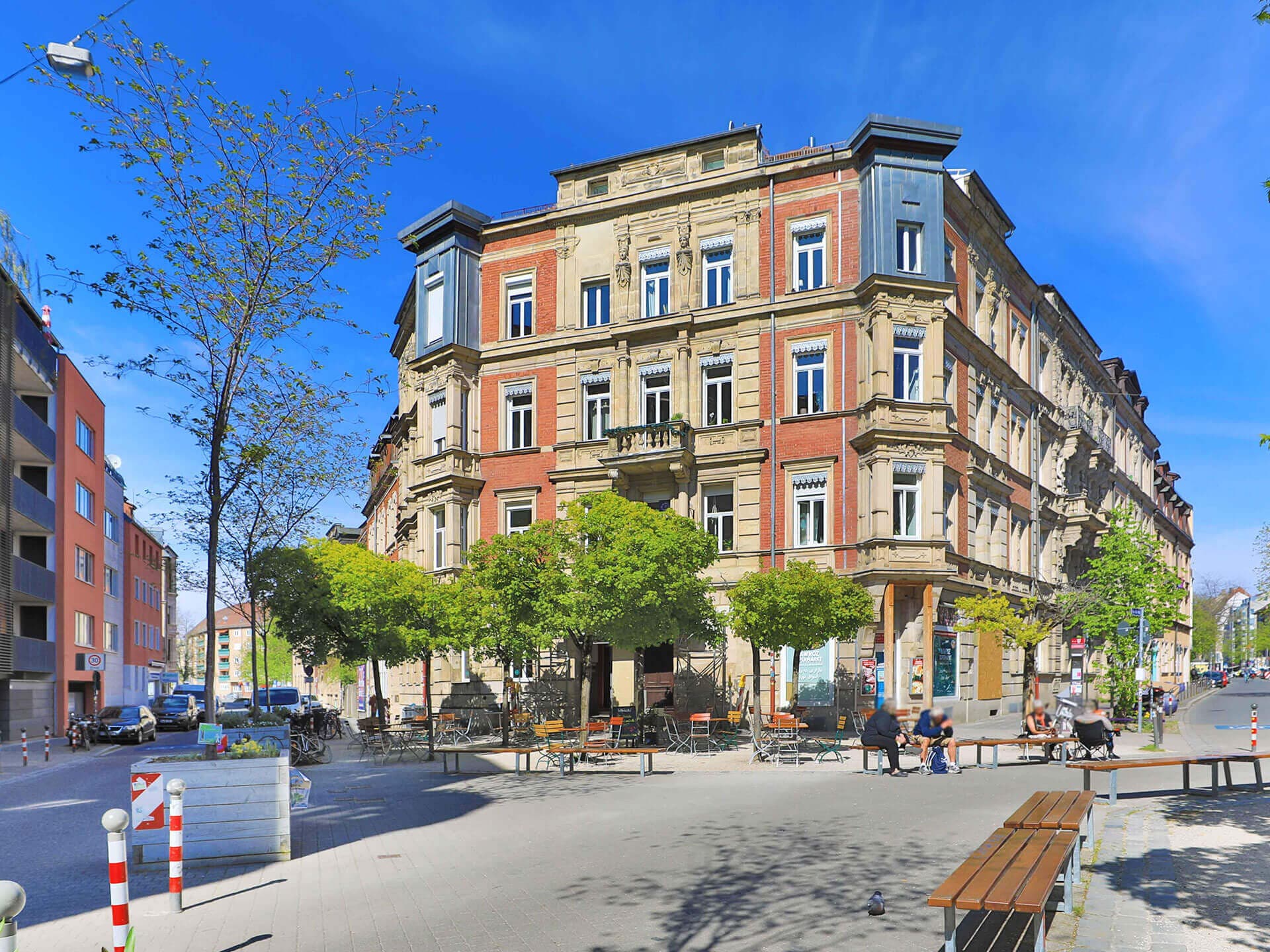 Gründerzeit-Eckhaus mit Sandstein- und Klinkerfassade an einem Platz mit Bäumen in Nürnberg-Gostenhof