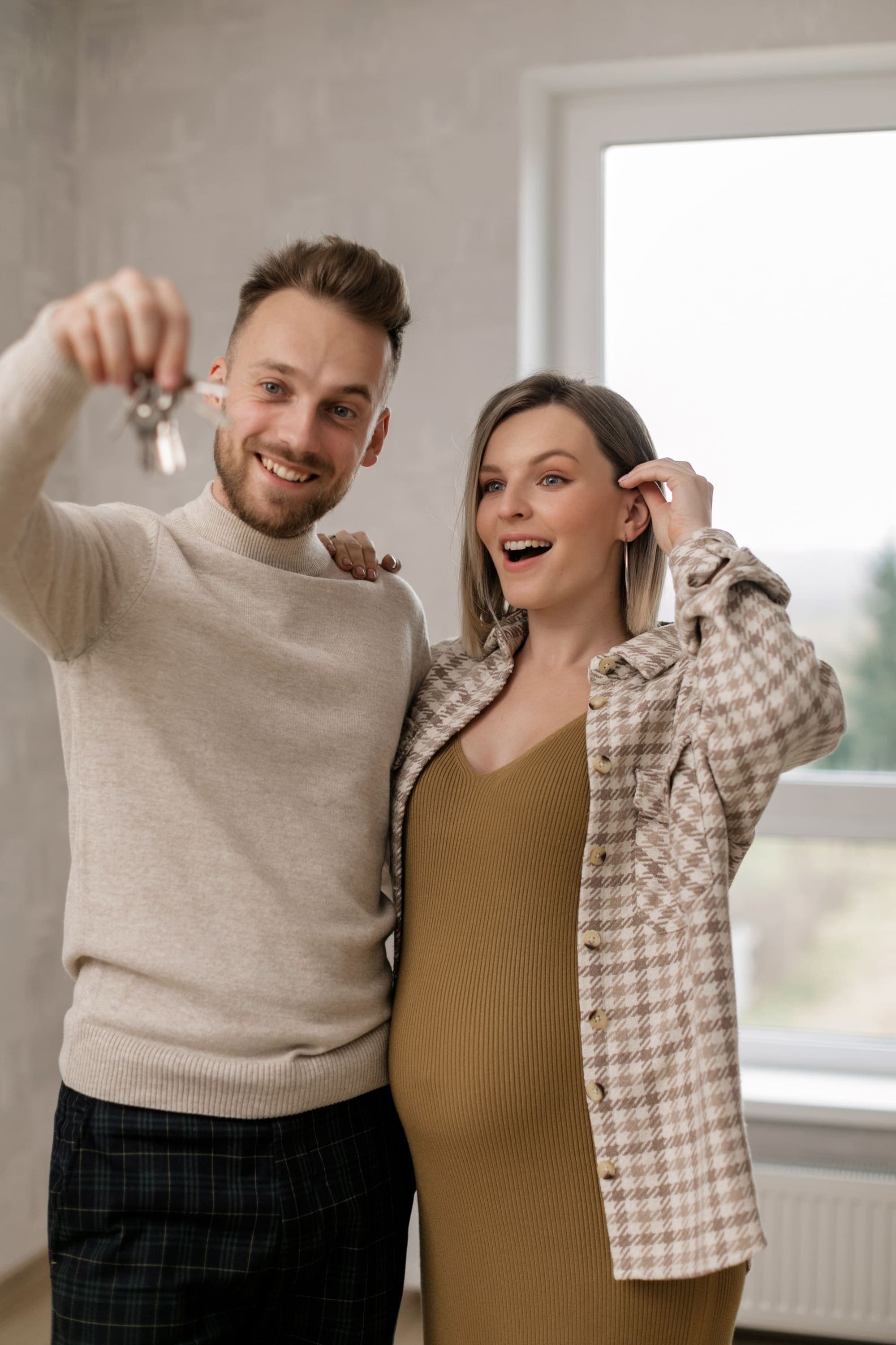 Ein Paar zeigt lachend den Schlüssel zur neuen Wohnung