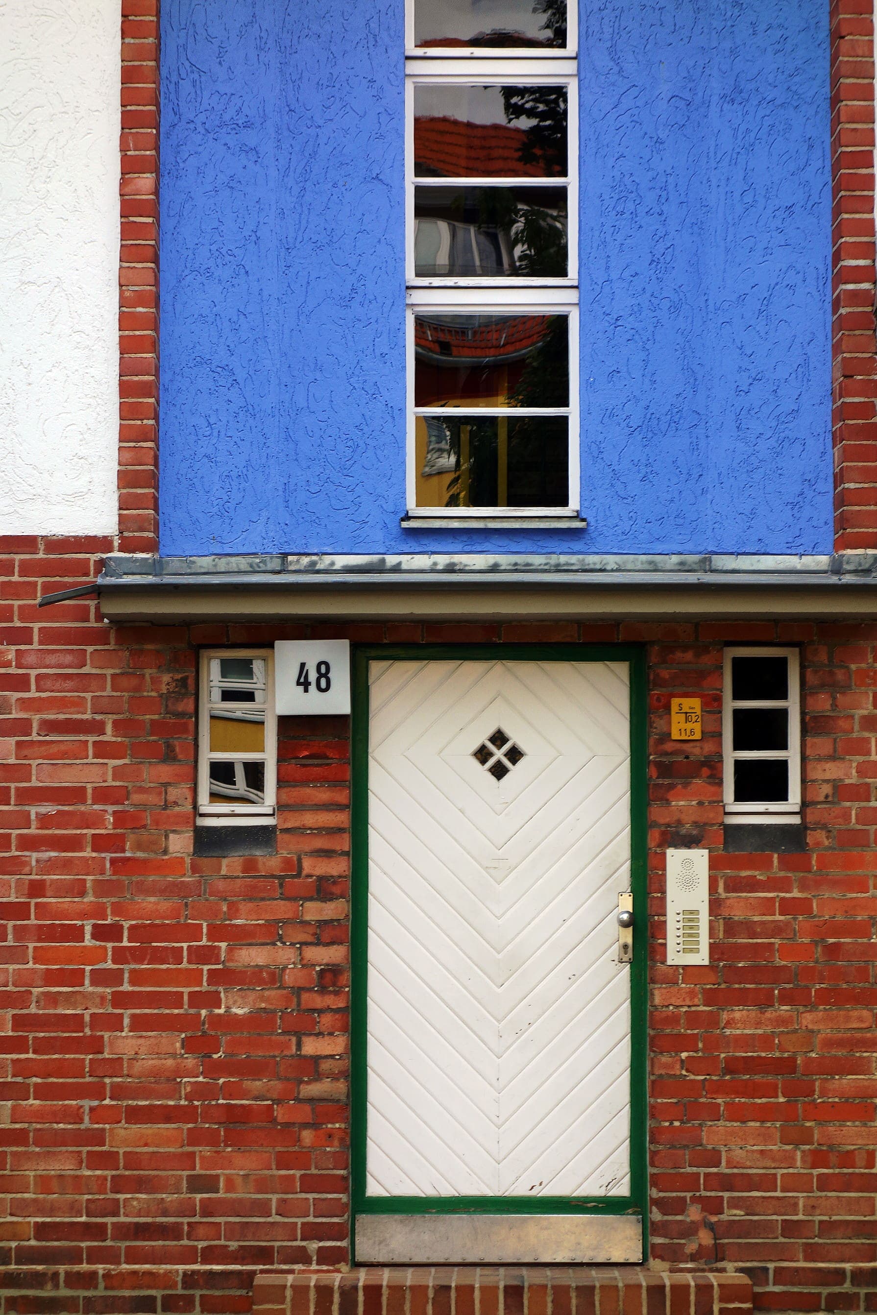 Weiße Haustür mit Hausnummer 48 in einer blauen Fassade der Hufeisensiedlung